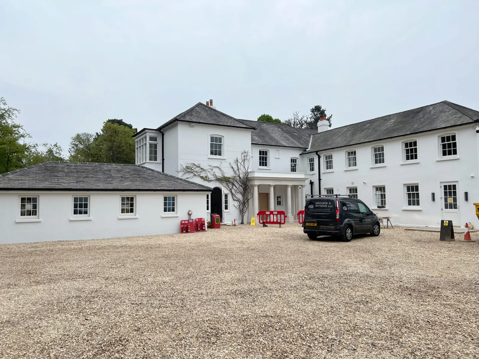 A white rendered weekend retreat with a gravel courtyard and a low service wing.