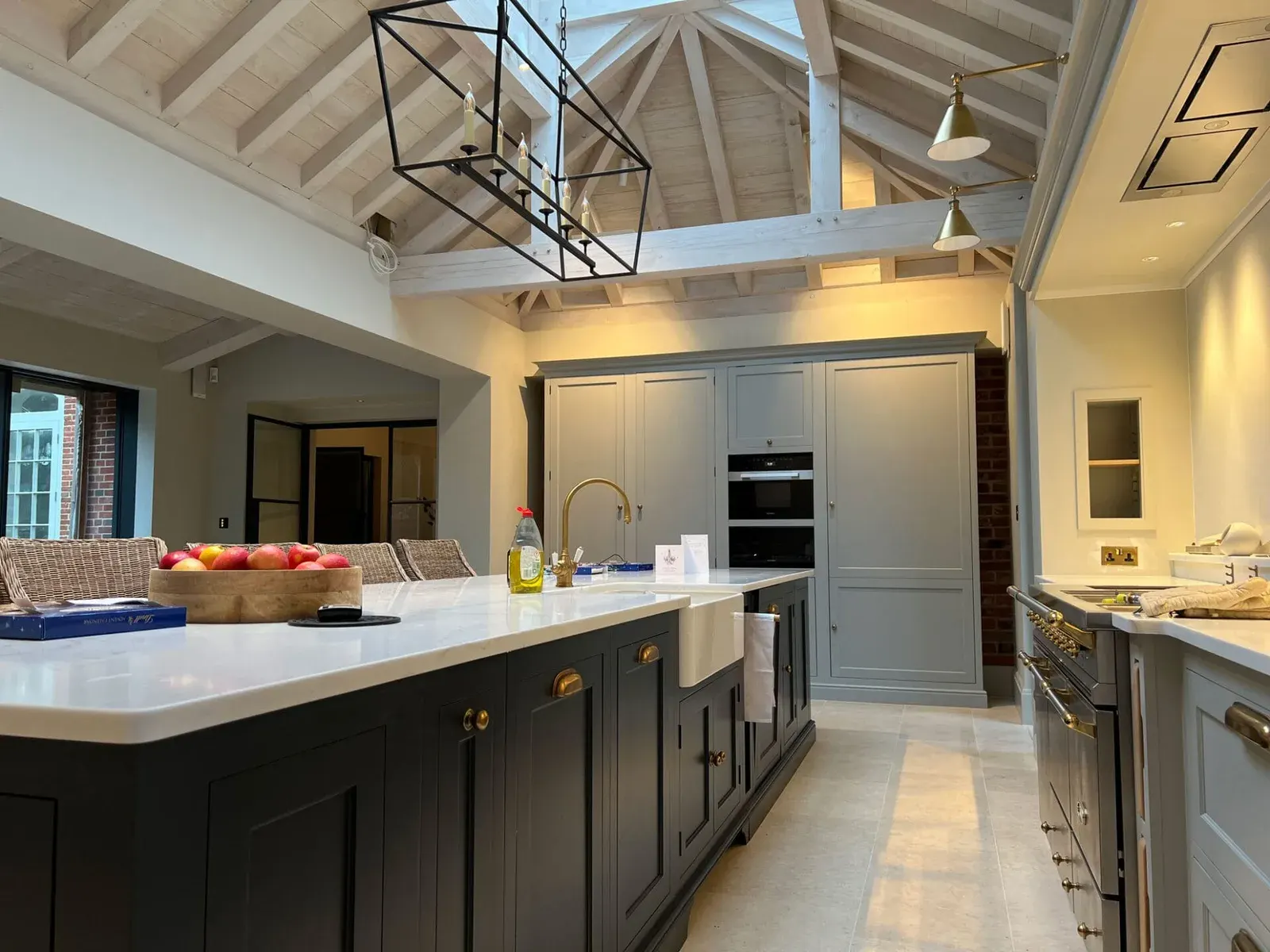 A completed kitchen with painted cabinetry beneath a whitewashed vaulted timber roof.