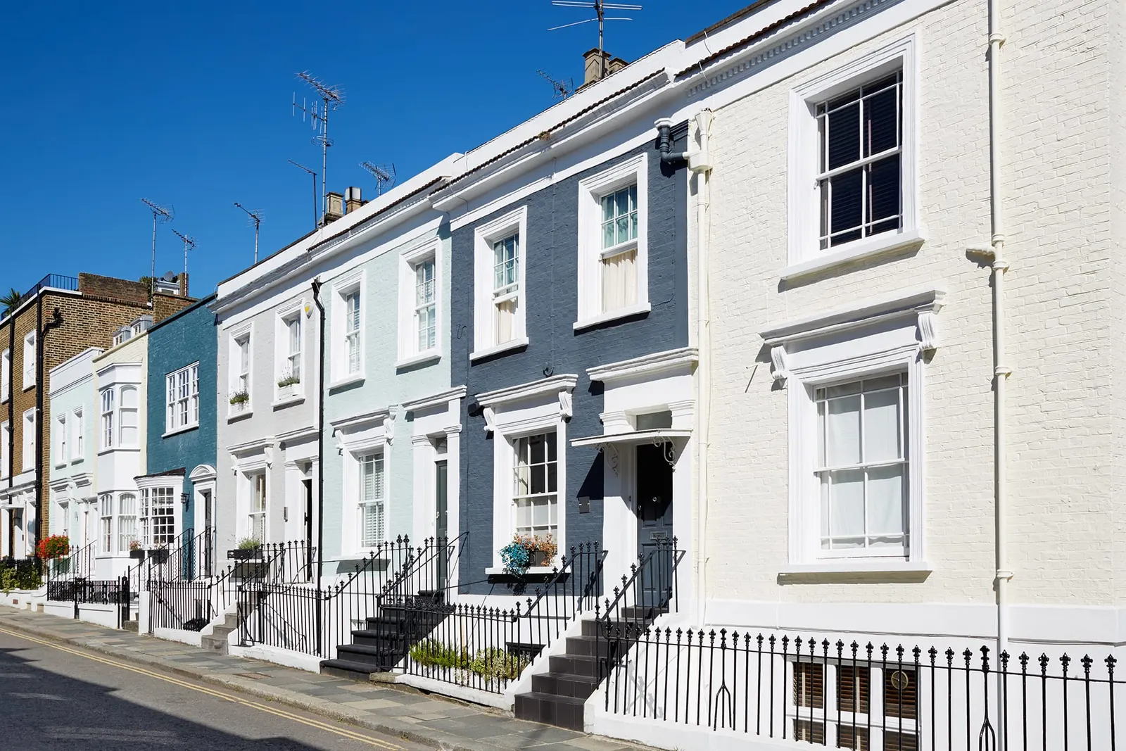 A row of painted period terraced houses under a clear blue sky.